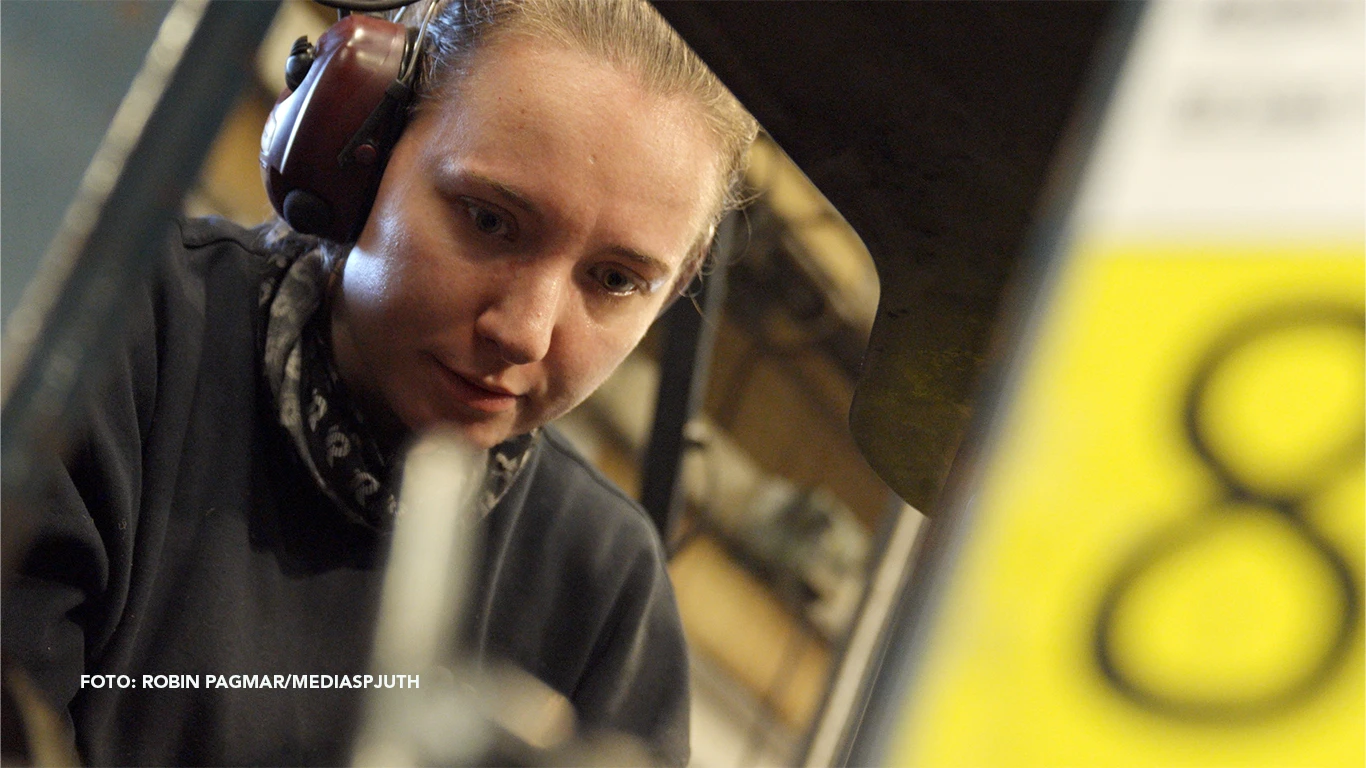 Sofie framför en industrimaskin. Sofie framför en industrimaskin.